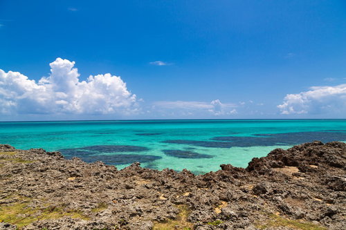 でこぼこした岩場の先に広がる池間島のエメラルドグリーンの海