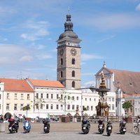 チェスケーブジェヨヴィツェの広場に駐車するバイクと時計塔の写真