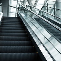現代的な建物内に並ぶ上りと下りのエスカレーターの写真