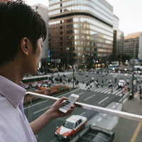 駅前でスマホを操作する待ち合わせ中の男性の写真