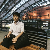 駅のベンチで疲れた表情を見せる就活中のビジネスマンの写真