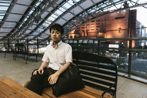 駅のベンチで疲れた表情を見せる就活中のビジネスマン