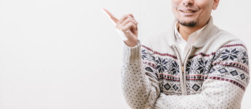 上方を指をさす笑顔の男性のポーズ