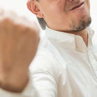 力強い表情で拳を握る男性の写真
