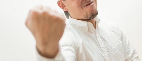 力強い表情で拳を握る男性