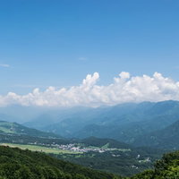 霞ゆく山々と街並みが見える青空と入道雲の風景の写真