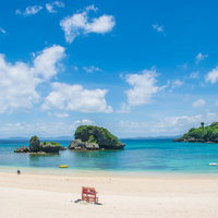 エメラルドグリーンの海が広がる夏の海水浴場の写真
