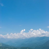 どこまでも続く青い空と霞ゆく山々と麓の町並みの写真