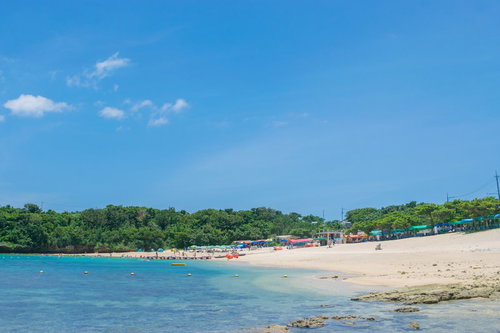 夏の海水浴場の砂浜と透き通った海、青空と白い雲