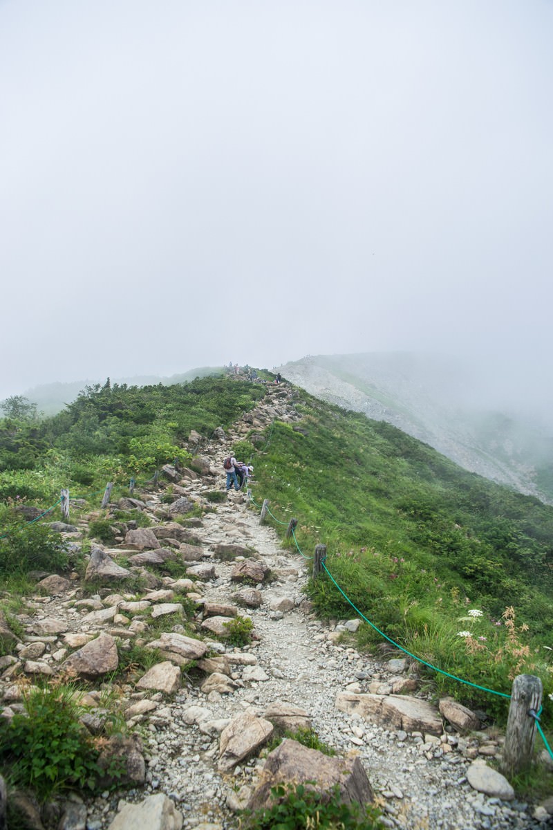 霧に包まれた山の稜線を蛇行して続く石段の登山道