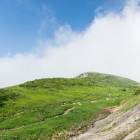 沸き立つ雲の中へと続く登山道を行く登山者の写真