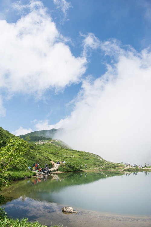 湖面に映る雲と登山者の山並み、トレッキングの風景