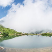 緑の山々に囲まれた湖畔で休む登山者たちの風景の写真