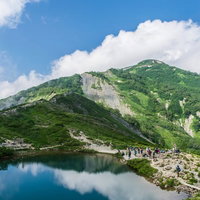 湖畔に映る山々と登山者の景色の写真