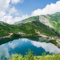水鏡に映る青空と登山者の山々の風景の写真