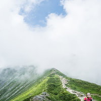 雲の中の尾根を進む登山者の後ろ姿と稜線の風景の写真
