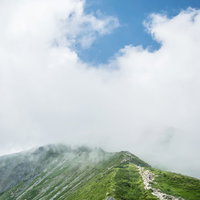 雲海に包まれた稜線を歩む登山者の山岳風景の写真
