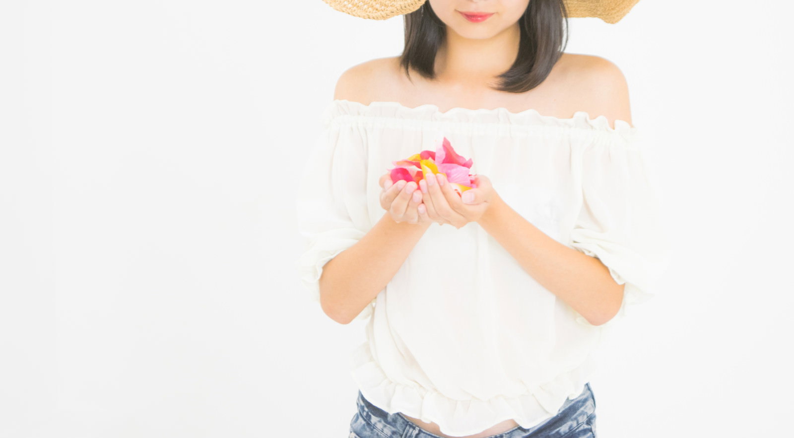 麦わら帽子を被った女性が両手で花びらを大切に包んでいる様子
