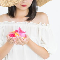 ピンクの花を手に抱える麦わら帽子の女性のポートレートの写真