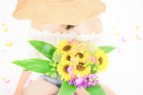 麦わら帽子の少女が持つひまわりのフラワーアレンジメント