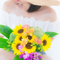 ヒマワリのブーケを持ちオフショルダートップスを着た女性の写真