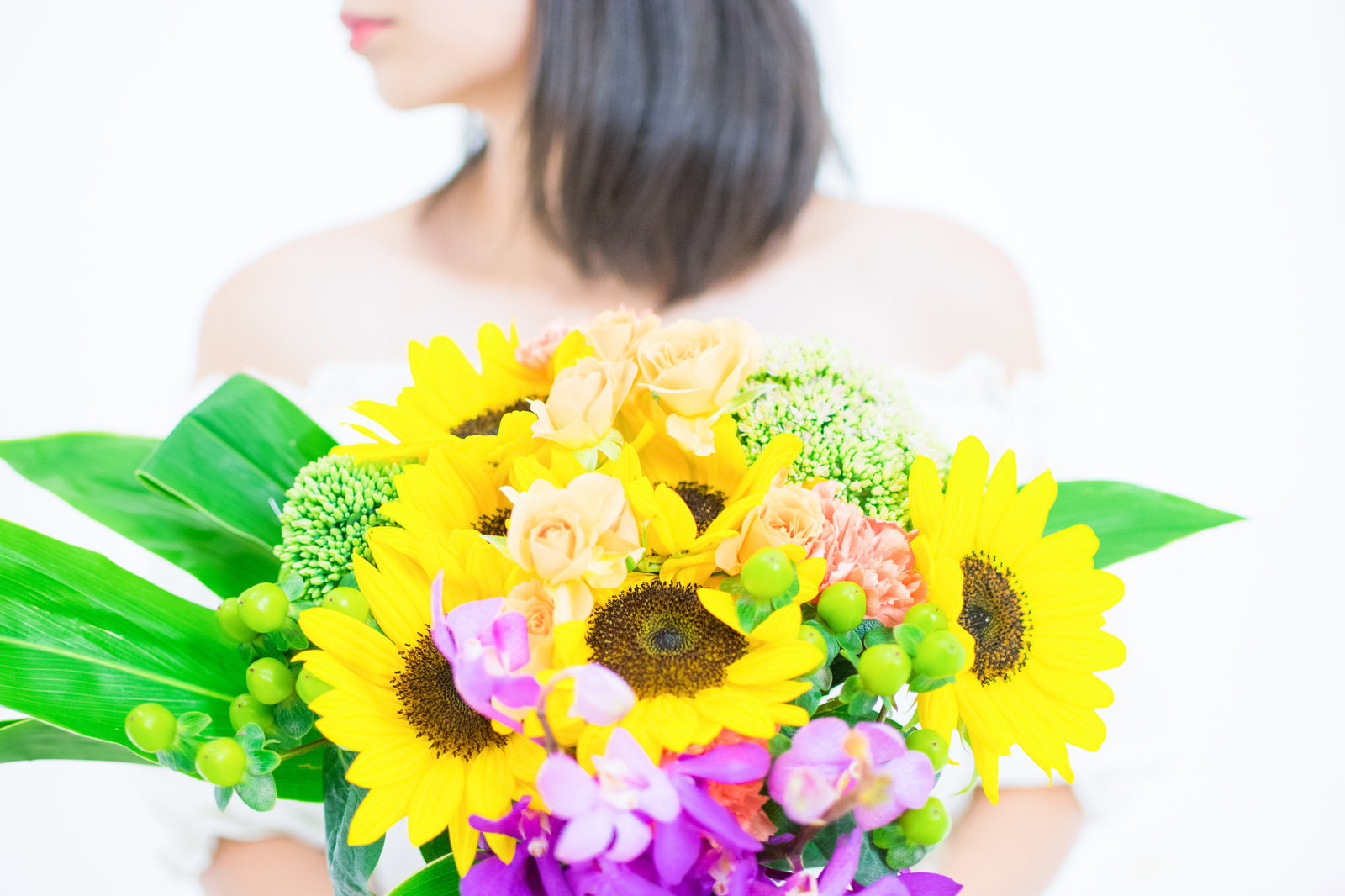 黄色いひまわりのブーケを両手で差し出している女性