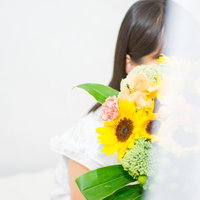 黄色いひまわりの花束を持ってスタンバイしている女性の写真