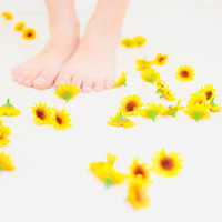 白い床に散らばるひまわりと素足、夏の季節の写真