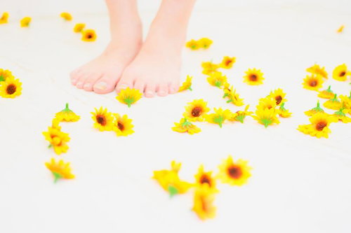 白い床に散らばるひまわりと素足、夏の季節