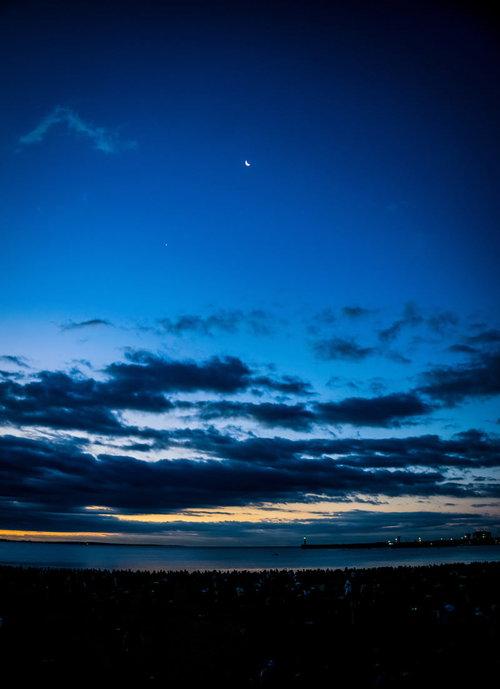 夜明け前の薄明な空に浮かぶ月と雲の地平線風景