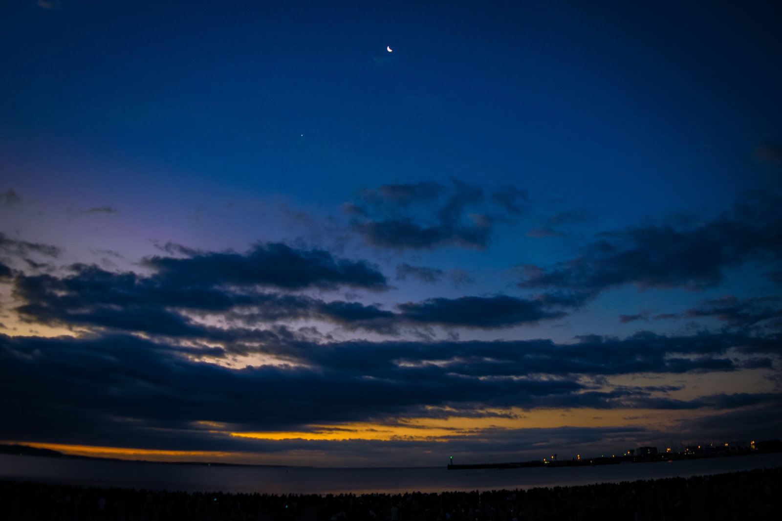 深い青色の夜明け前の空にオレンジ色の朝焼けが地平線に広がる風景