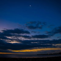 夜明け前の空に広がるオレンジ色の朝焼けと月の写真