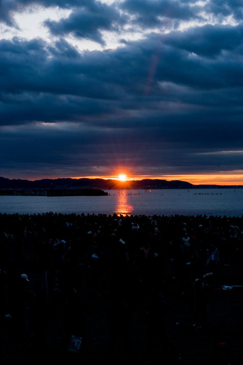 厚い雲間から現れる朝日と海面に映る光の夜明け風景
