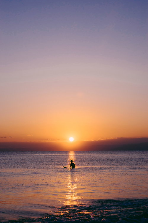 夕暮れのレイラインで波待ちするサーファー男性