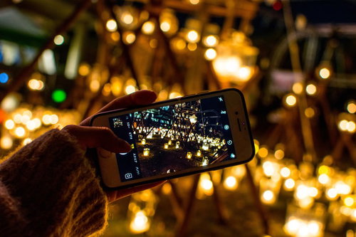 ライトアップされた光景をスマートフォンで撮影する手元
