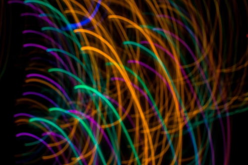 黒い背景に流れるカラフルな光跡 虹色グラデーション