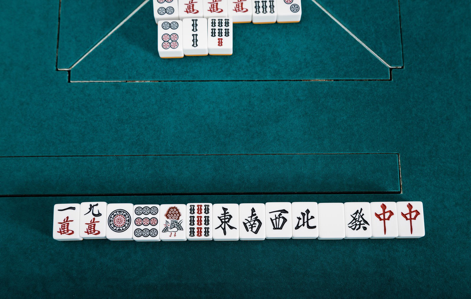 麻雀卓で国士無双をツモ和了りした配牌の写真。緑の卓上に白い牌が配置されている