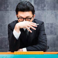 あンた背中が煤けてるぜ。闘牌の男性が麻雀卓でリーチを仕掛けるの写真