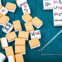 闘牌の流局の瞬間：緑色の卓で散らばる麻雀牌と配牌の積み重ねの写真