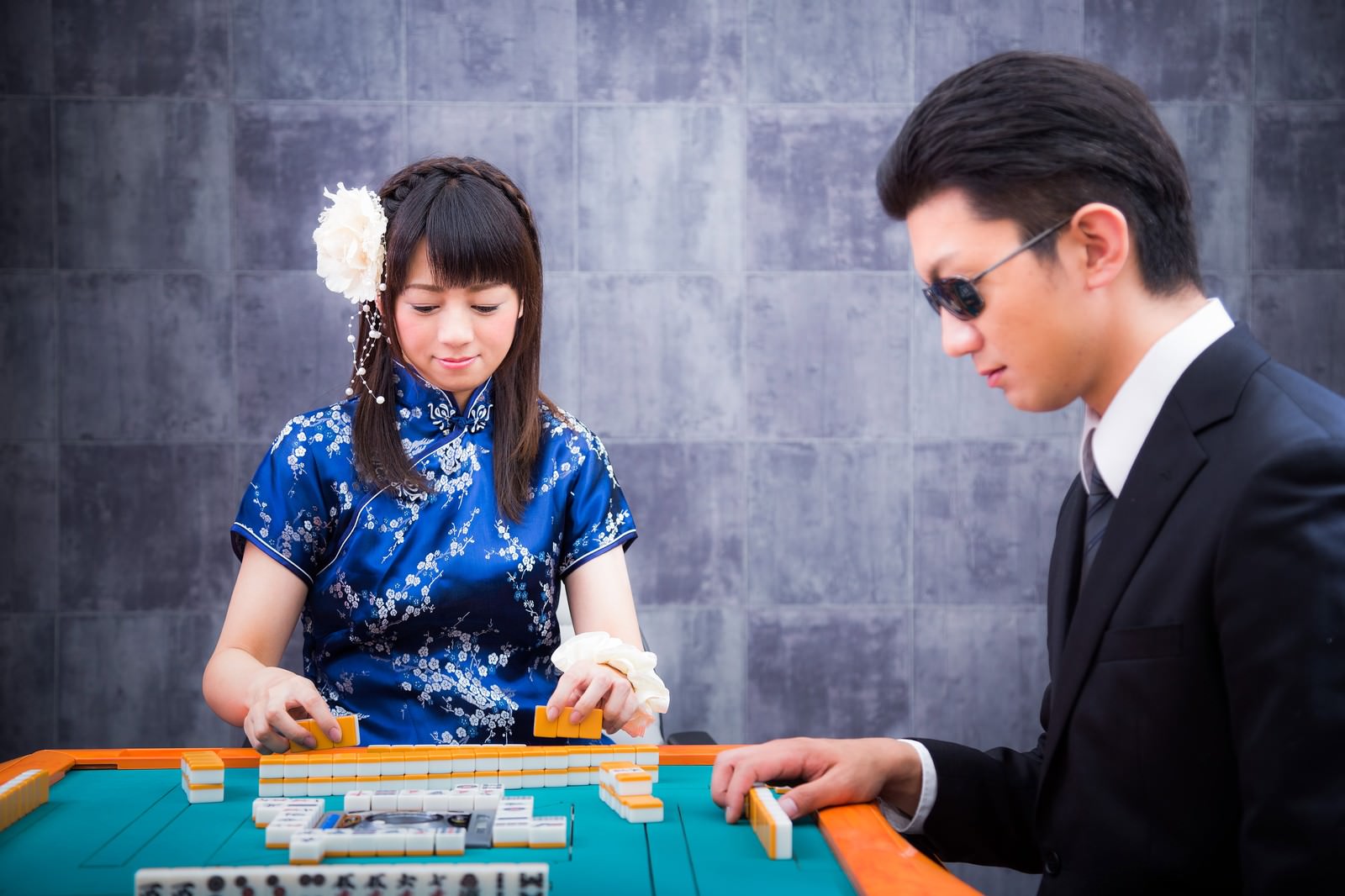 麻雀卓で対局する女流雀士と黒服の男性［モデル：米崎奈棋 OZPA］