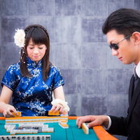 緊張する黒服の代打ちと手牌を整える女流雀士の写真
