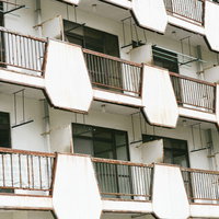 入居者がいない錆びたバルコニーのマンションの写真