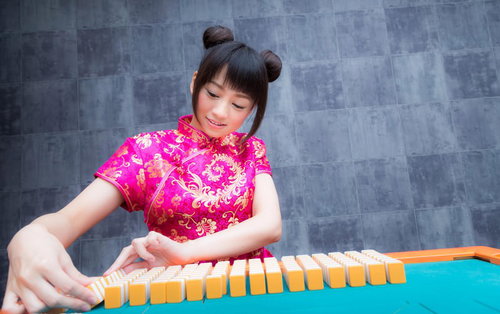 チャイナ服姿で麻雀卓を掃く女流雀士のプロ雀士