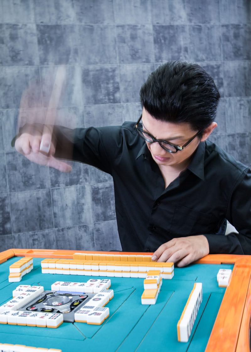 麻雀テーブルで牌を叩きつけるマナー違反の行為をする男性［モデル：OZPA］