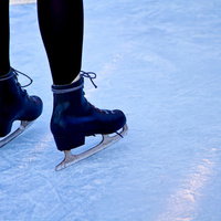 氷の上に立つ青いスケート靴とアイススケートの足元の写真