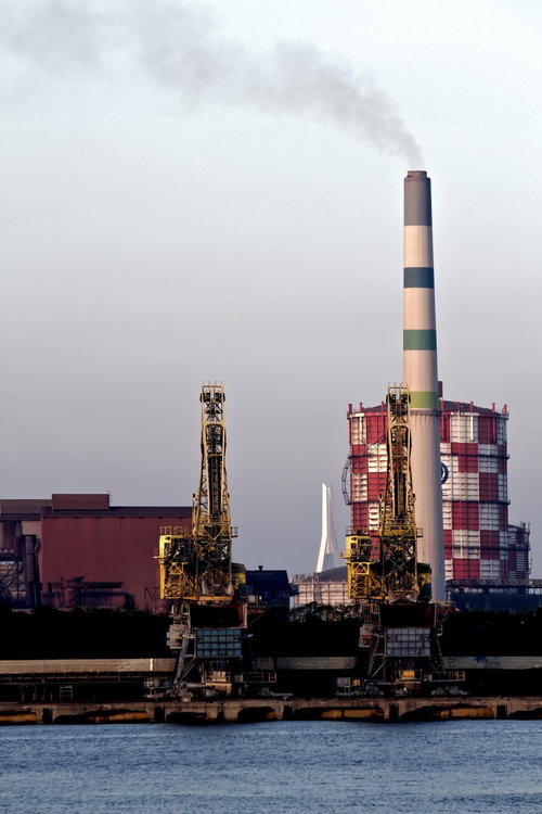 夕方の水辺に並ぶ掘削機と川崎の沿岸の工場