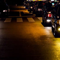黄色い表示灯を点けて客待ちする夜のタクシーの列の写真