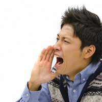 口に手を当てて大きな声で叫ぶ青年の写真