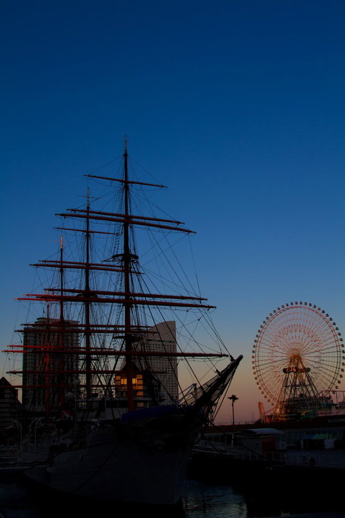 夕暮れの港に浮かぶみなとみらいの観覧車と帆船日本丸