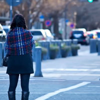歩道で後ろ姿を見せて信号待ちをする女性の写真
